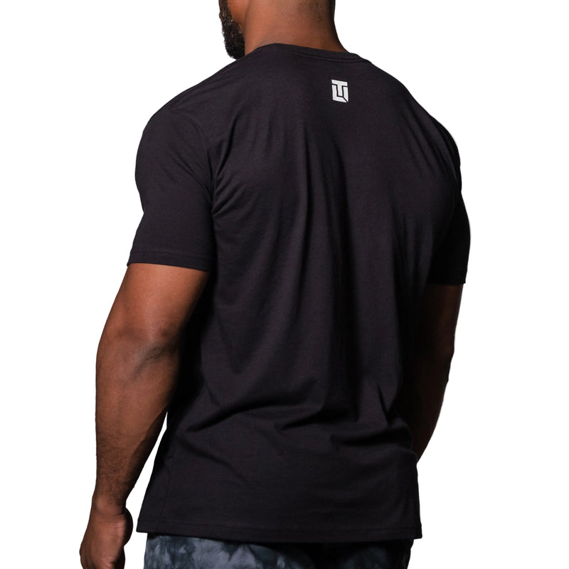 Load image into Gallery viewer, Person wearing a black t-shirt with a logo on the back against a gray background