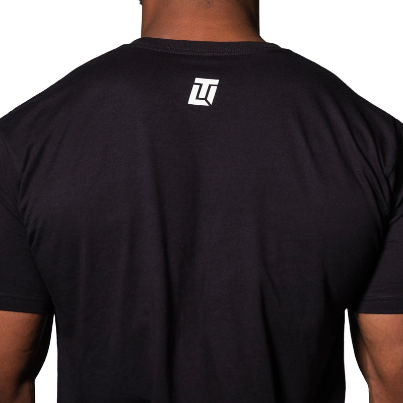 Load image into Gallery viewer, Black t-shirt with a logo on the back against a gray background