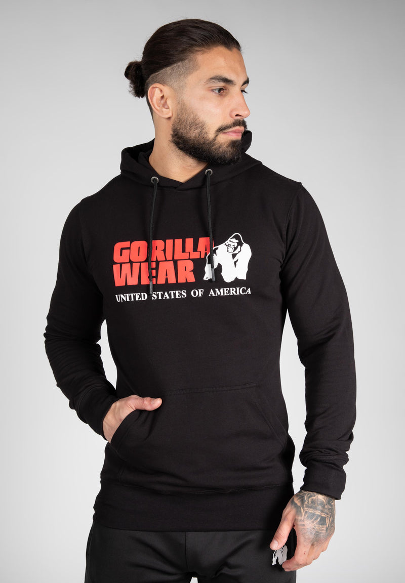 Load image into Gallery viewer, A male model wearing a black hoodie with the Gorilla Wear logo on the chest. The hoodie features a drawstring hood and elastic ribbed cuffs.