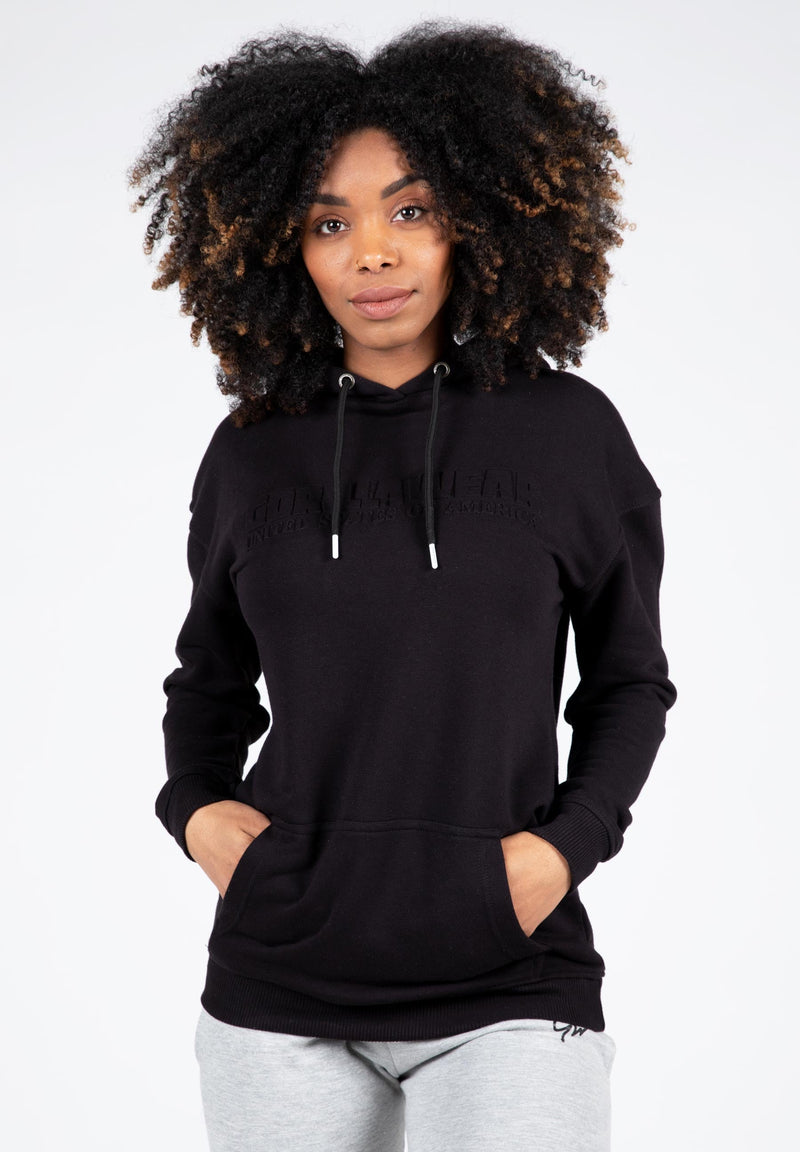 Load image into Gallery viewer, A woman wearing a black oversized hoodie with a hood, featuring a relaxed fit and drop shoulders.