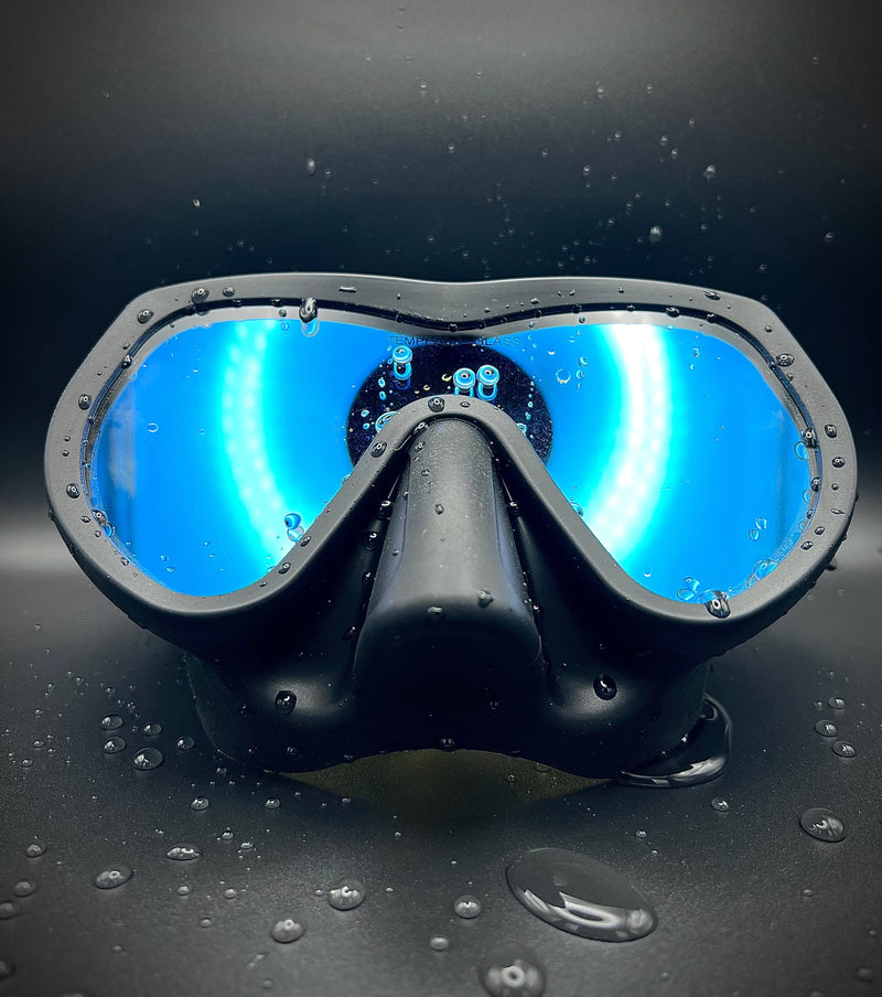 Load image into Gallery viewer, Black diving mask with blue lenses on a dark background
