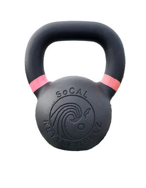 Black kettlebell with pink accents on pebbles by the ocean